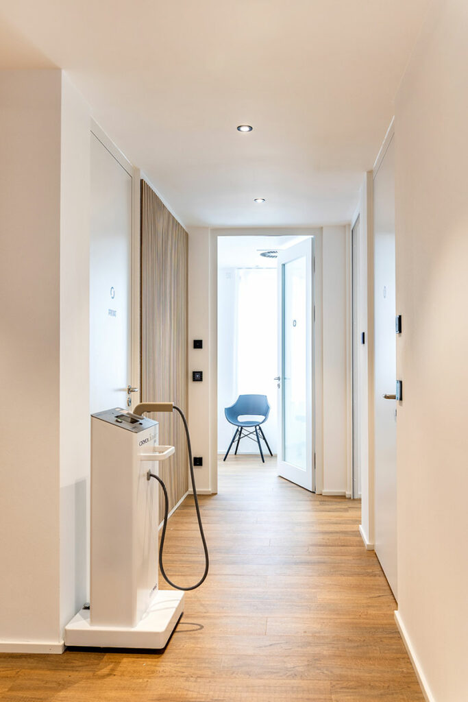 Flur im ROC Orthopädie Aschheim in München mit CryoLight-Gerät und Blick in einen hellen Behandlungsraum mit moderner Einrichtung.