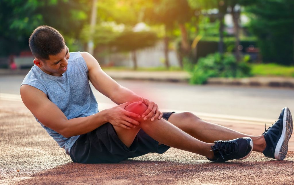 A young man is sitting on the floor after a sports injury, holding his knee—meniscus adhesion and meniscus repair at the ROC—Regenerative Center in Aschheim